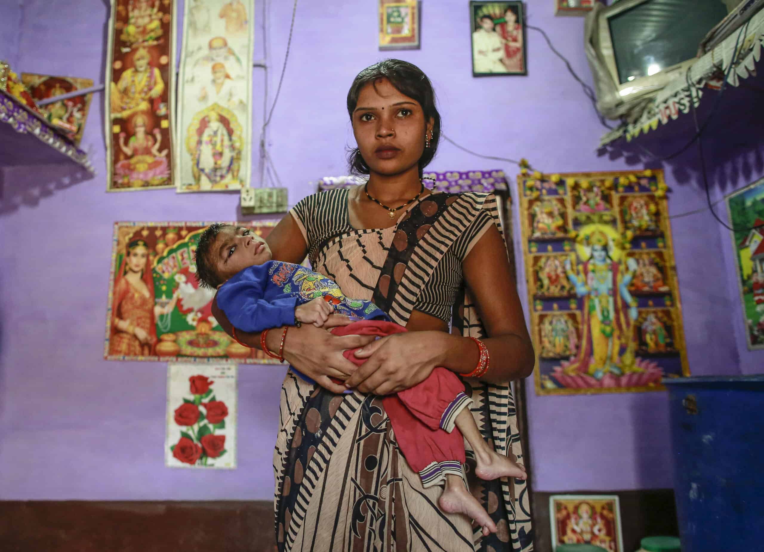 Five year old Saagar, who suffers from mental and physical disabilities is held by his mother Komal, as she poses for a picture at their house in a slum in Bhopal
