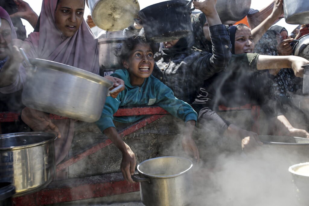 Displaced Palestinians collect donated food in Gaza City